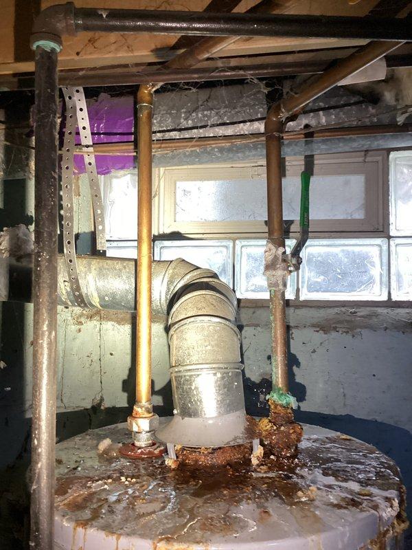 Conducted an estimate for water heater replacement options, including both tankless and traditional tank models. Existing unit shows significant corrosion and rust on top surface with compromised connections. Installation environment includes limited access in utility area with exposed plumbing, ductwork, and block glass window, requiring careful consideration for replacement logistics.