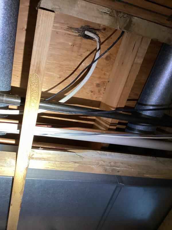 Conducted comprehensive assessment for kitchen remodel estimate, inspecting existing PVC drainage system with multiple pipe sections and associated brass fittings. Evaluated structural framework in crawlspace/between floor joists, documenting condition of plumbing infrastructure and electrical wiring pathways to determine scope of work required for renovation project.