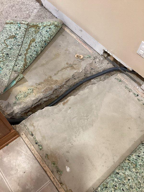 Completed subpanel relocation requiring concrete floor demolition to access and reroute existing electrical conduit. Removed cabinet shelving to accommodate new electrical junction box installation and properly secured conduit through cabinet interior for code compliance.