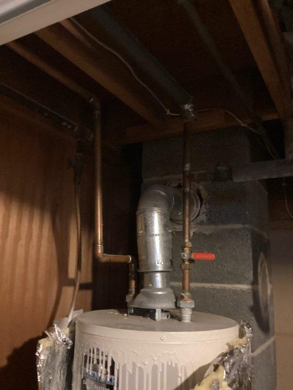 Responded to emergency water heater leak call for 20+ year old Bradford White unit with extinguished pilot. Inspection revealed significant water discharge from upper seam, indicating tank failure. Installed temporary insulation wrap to contain leakage and advised immediate replacement due to irreparable tank deterioration and age of unit.
