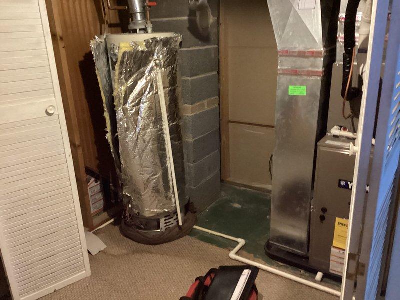 Responded to emergency water heater leak call for 20+ year old Bradford White unit with extinguished pilot. Inspection revealed significant water discharge from upper seam, indicating tank failure. Installed temporary insulation wrap to contain leakage and advised immediate replacement due to irreparable tank deterioration and age of unit.