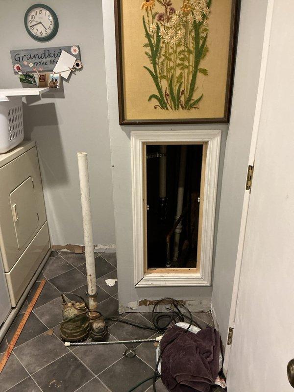 Inspected sump pump system following reports of previous failure and flooding. Accessed wall panel to evaluate plumbing infrastructure where significant corrosion was observed on copper pipes and fittings. Replaced failed sump pump with new unit after confirming motor burnout, ensuring proper installation and function to prevent future basement flooding.