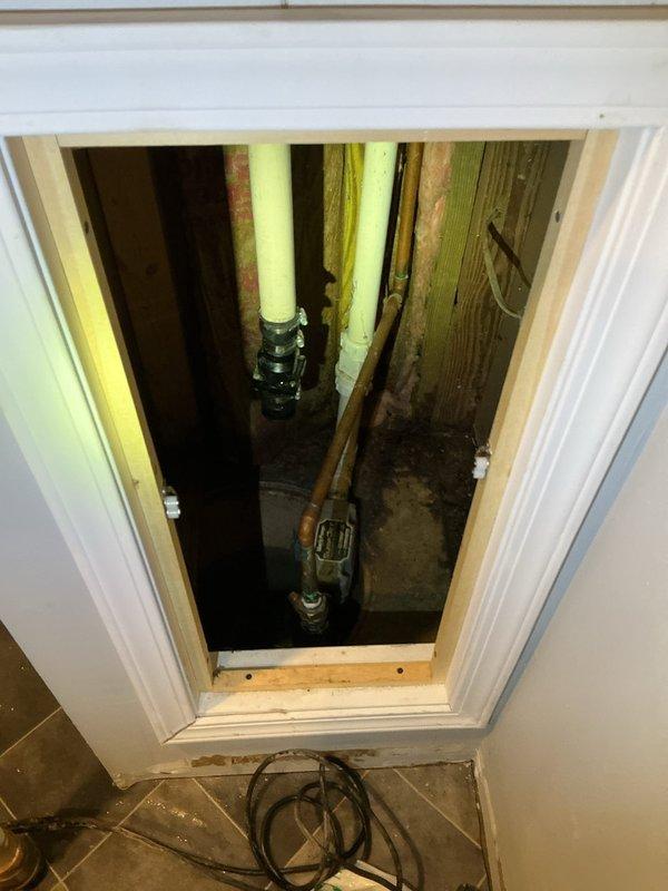 Inspected sump pump system following reports of previous failure and flooding. Accessed wall panel to evaluate plumbing infrastructure where significant corrosion was observed on copper pipes and fittings. Replaced failed sump pump with new unit after confirming motor burnout, ensuring proper installation and function to prevent future basement flooding.