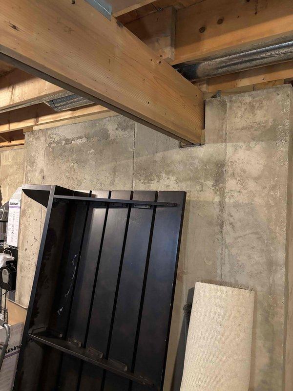 Responded to water leak service call for 9-year-old Bryant system. Inspected basement area showing water damage and staining on concrete walls. Examination of plumbing components revealed leakage from deteriorated plastic tubing connections under the fixture, which were replaced and secured with proper mounting clips to prevent future leakage.