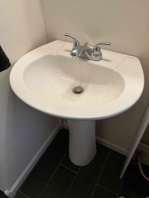 Responded to service call for leaking bathroom pedestal sink reported to have started the day of service. Upon inspection, identified mineral buildup on chrome faucet contributing to leak. Repaired leak by replacing worn components and clearing calcium deposits from affected areas, restoring proper functionality to the sink.