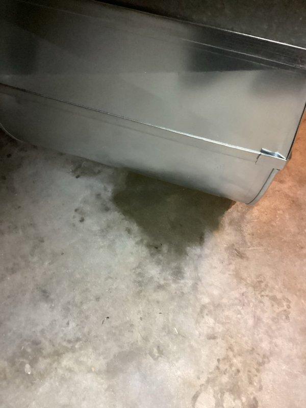 Responded to water leak service call for 0-year-old Carrier WT 10-2035 furnace. Inspection revealed significant water damage to wooden wall panel near unit with visible moisture on concrete floor. Documented extensive water staining along wood grain indicating prolonged exposure.