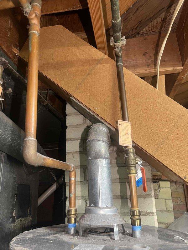 Conducted a water heater inspection on a 9-year-old Rheem unit that was actively leaking from the bottom. Documentation included photos of the existing plumbing setup, showing copper supply lines with brass fittings, galvanized vent piping, and the current installation configuration against brick wall in utility area. Provided customer with replacement options.