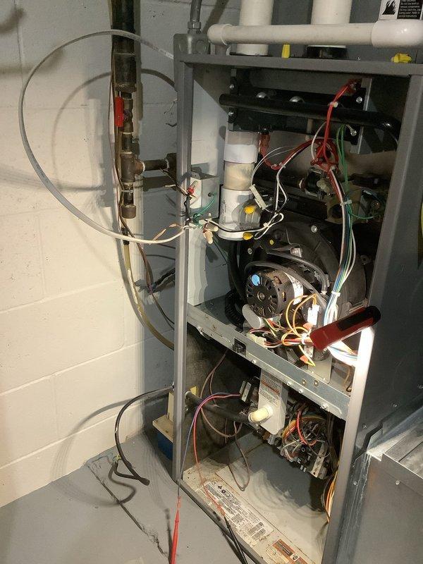 Performed diagnostic inspection on non-functioning HVAC system, accessing internal components including circuit board, motor, and wiring connections. Inspection of electrical panel revealed cluttered wiring with potential connection issues affecting furnace operation; restored proper electrical connections and verified system operation before closing access panels.