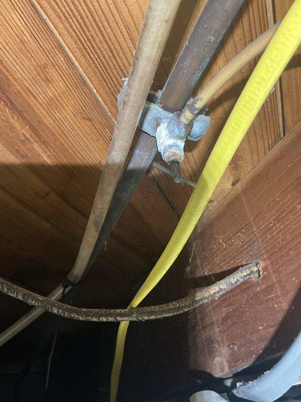 Performed annual heating tune-up on 9-year-old Luxaire furnace for Comfort Club member. Observed significant corrosion and mineral buildup on copper pipe connection to water heater with deteriorated sealing material. Noted yellow gas line and metal piping installation in crawlspace between floor joists requiring attention.