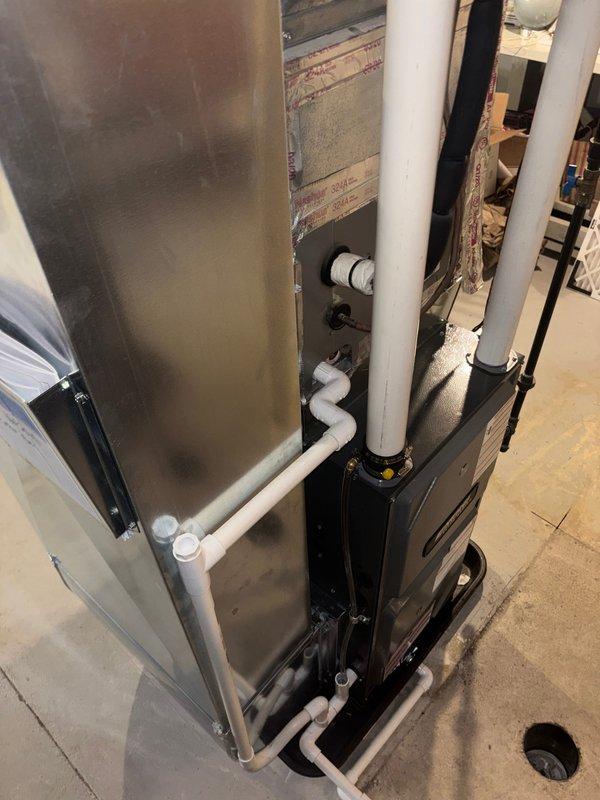 Successfully installed new furnace unit in basement utility area, connecting all necessary white PVC ventilation pipes and drainage lines to existing HVAC system. Unit was properly mounted on concrete floor adjacent to water heater, with all connections secured and system tested for proper operation.