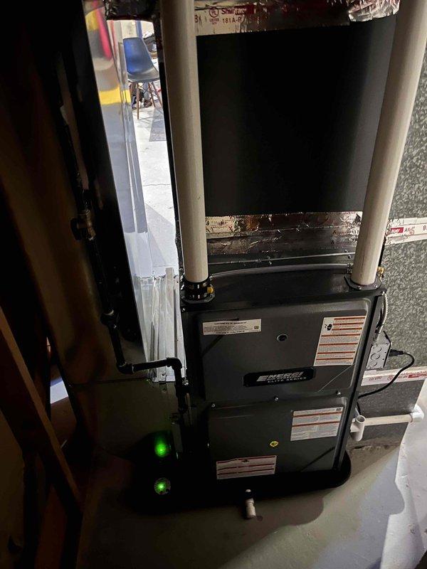 Successfully completed installation of new energy-efficient furnace with dual PVC ventilation system. Unit was properly mounted on concrete floor in utility space with all necessary connections to existing plumbing and mechanical systems. System was tested and confirmed operational as evidenced by active indicator lights.