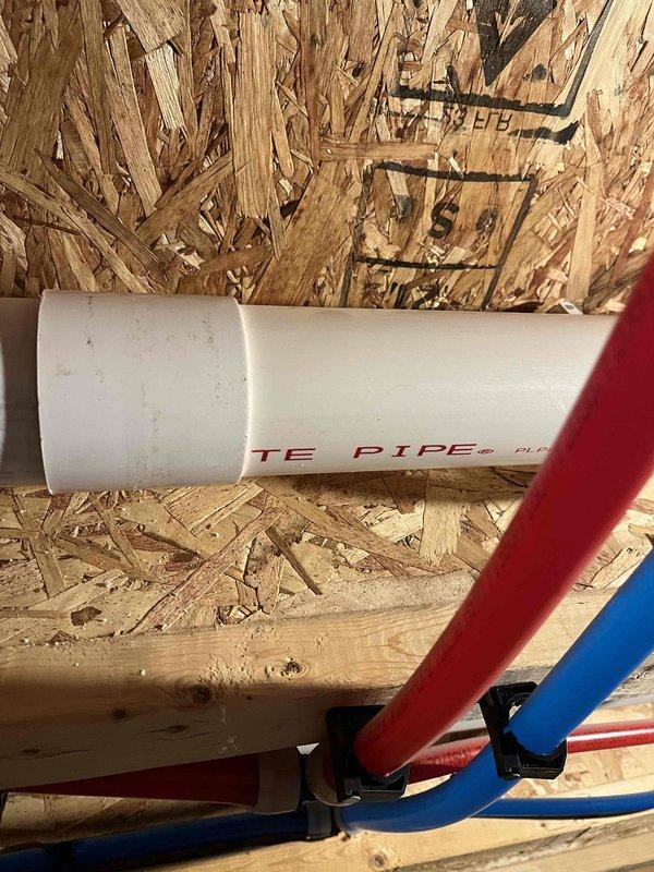 Returned to complete quoted toilet repair service. Inspected toilet mounting system and connection to floor. Verified proper installation of plumbing supply lines (PVC, red and blue pipes) secured with appropriate brackets against OSB wall structure.