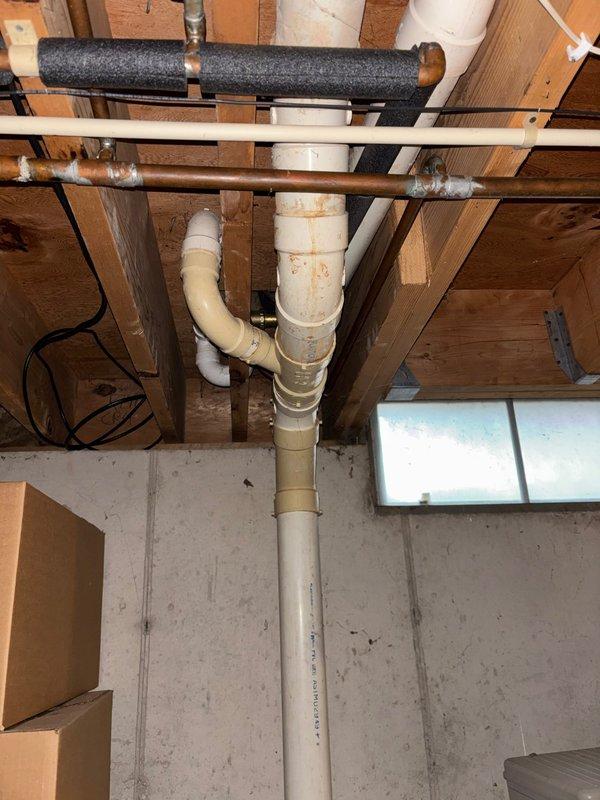 Successfully replaced kitchen faucet and cleared tub blockage using drain rodding equipment. Inspected basement plumbing infrastructure including vertical PVC drain pipe with rusty-brown discoloration and confirmed proper water heater operation with no leaks present.