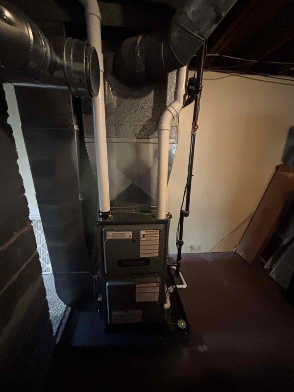 Successfully installed new residential furnace system in basement utility area, including proper connection of ductwork, PVC intake/exhaust venting, and condensate drain lines. System includes digital control panel and replacement air filters, with all components secured and operational according to manufacturer specifications.