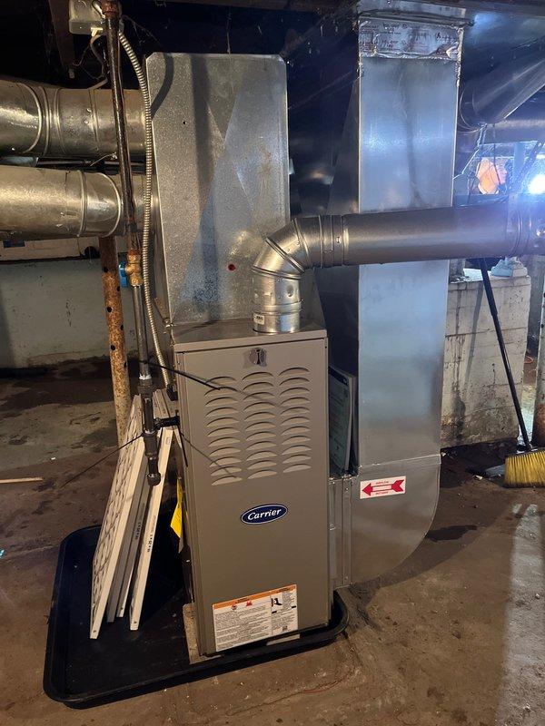 Successfully completed installation of Carrier furnace and white cylindrical water heater in basement utility area. Furnace was properly connected to existing ductwork with metal plenum box and return air system, while water heater was installed with copper piping connections and positioned on a metal drain pan. Both units were tested for proper operation and verified to be functioning correctly.