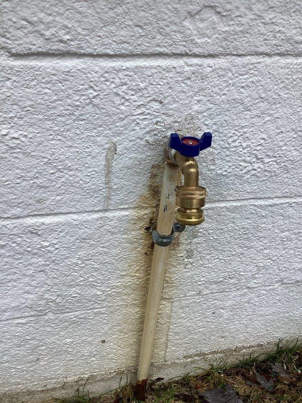 Replaced deteriorated outdoor spigot on concrete block wall exhibiting significant leakage. Installed new quarter-turn valve with blue butterfly handle, ensuring proper connection to existing PVC supply line. System tested with no leaks and full functionality restored.