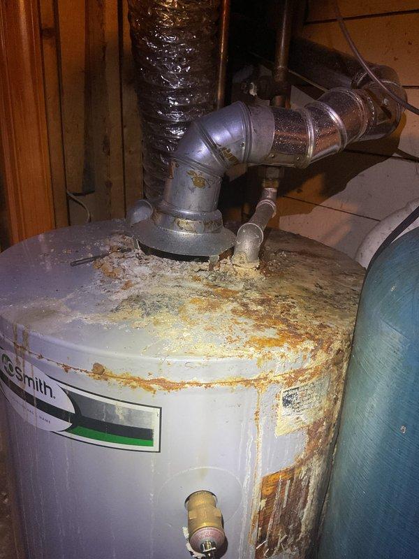 Performed complimentary annual furnace tune-up on 12-year-old Carrier system. Observed significant corrosion and rust on Smith water heater tank requiring attention, with deterioration visible at top surfaces, sides, and base. Noted secondary blue water treatment tank appears to be in better condition than primary unit.