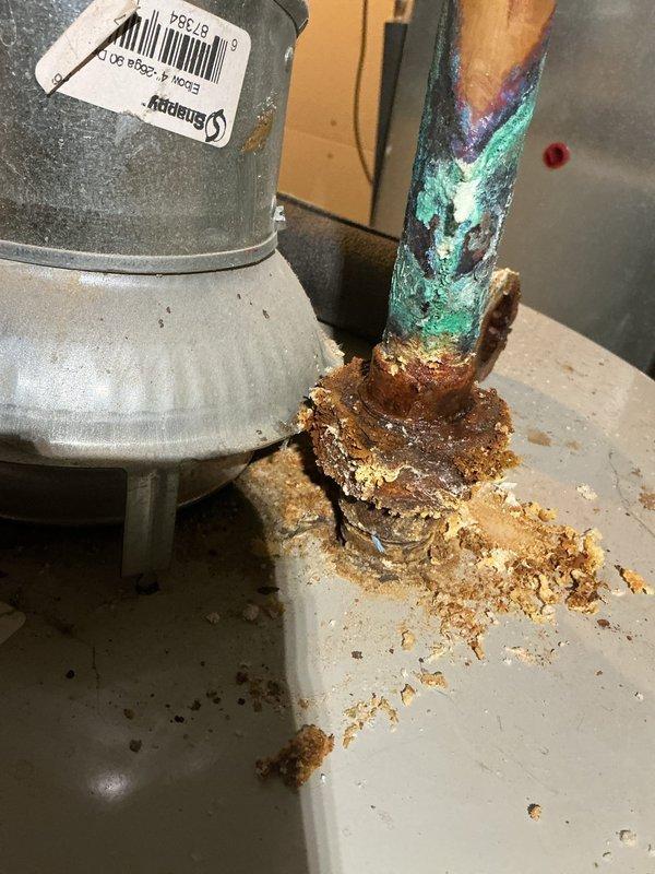 Completed annual heating maintenance service on furnace system. Identified significant corrosion and mineral buildup at water heater pipe connections, with active leakage evident at copper pipe junction. Documented severe oxidation of copper components showing blue-green patina and compromised connection integrity requiring attention.