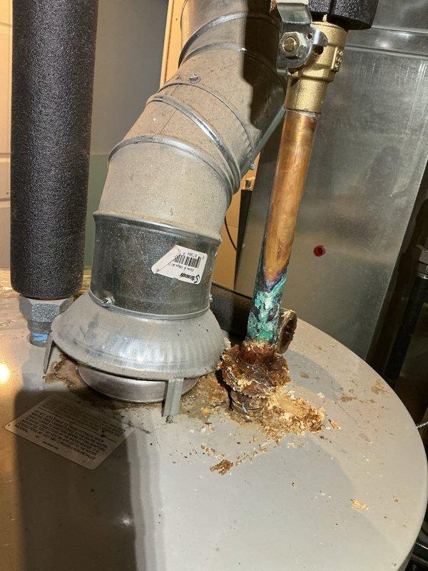 Completed annual heating maintenance service on furnace system. Identified significant corrosion and mineral buildup at water heater pipe connections, with active leakage evident at copper pipe junction. Documented severe oxidation of copper components showing blue-green patina and compromised connection integrity requiring attention.