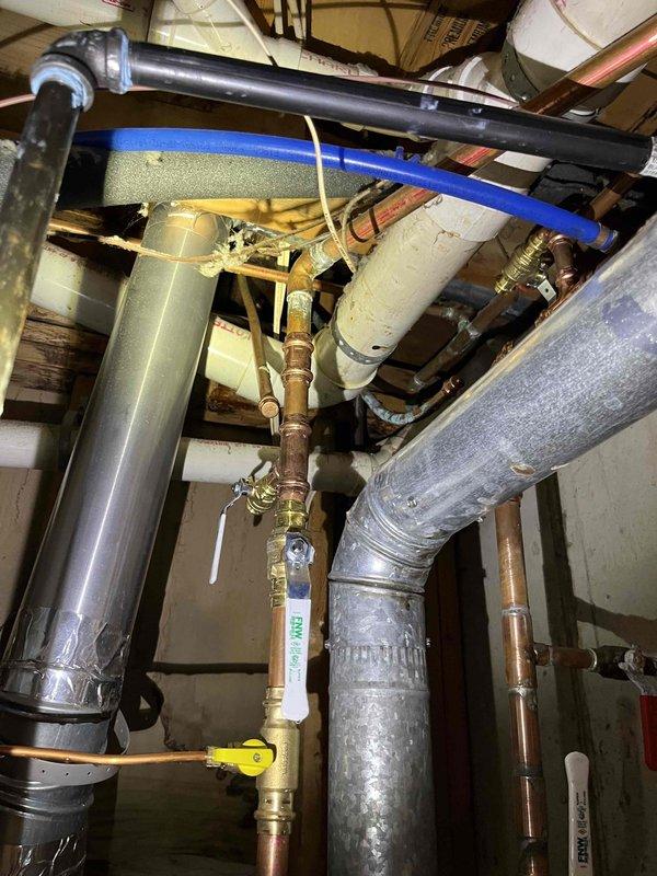 Investigated water leak from upstairs to basement above newly installed water heater. Inspection revealed deteriorated shower valve assembly with corroded seals and mineral deposits causing water to track down to basement through the pipe chase. Replaced valve cartridge and resealed fixture to wall, resolving the leak issue.