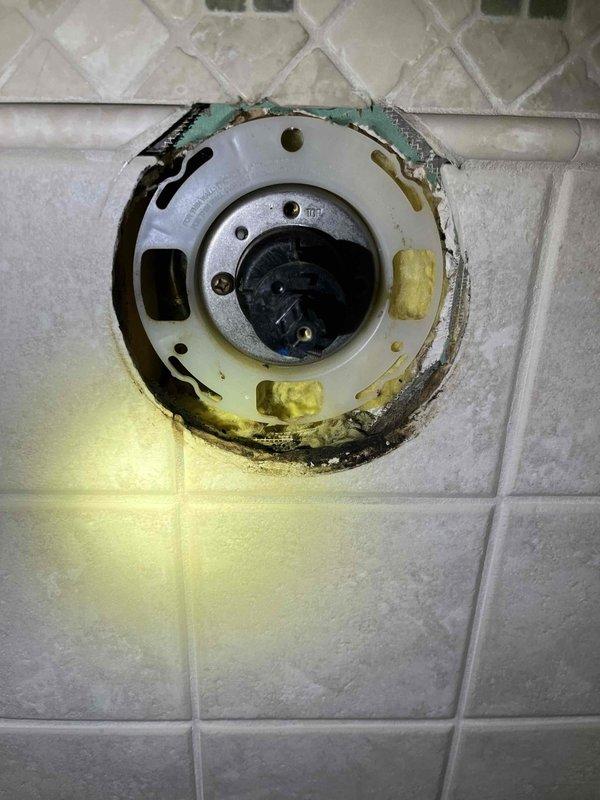 Investigated water leak from upstairs to basement above newly installed water heater. Inspection revealed deteriorated shower valve assembly with corroded seals and mineral deposits causing water to track down to basement through the pipe chase. Replaced valve cartridge and resealed fixture to wall, resolving the leak issue.