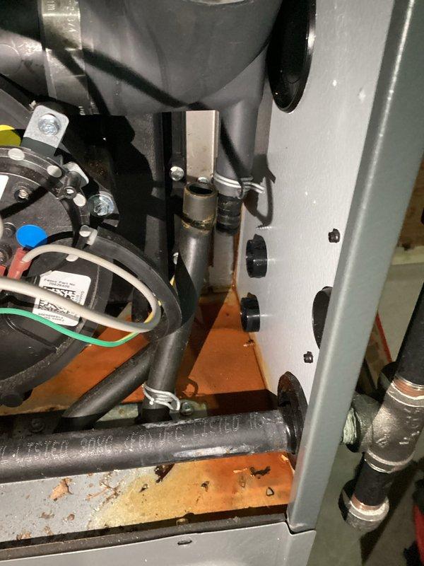 Responded to water leak between hot water heater and furnace drain on 7-year-old Carrier Energy series HVAC system. Inspected installation area showing water stains on concrete floor and identified leak point at connection between furnace condensate line and drainage system. Repaired damaged connection and verified proper drainage function to resolve the issue.