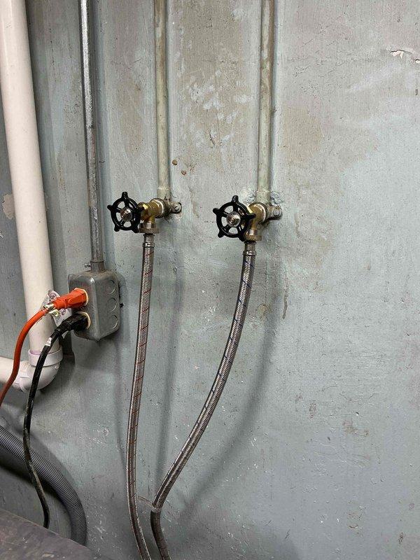 Successfully completed installation of new washer hook-ups, replacing the existing fixtures with two brass water valves featuring black star-shaped handles. Installed new braided stainless steel supply lines and verified proper operation with no leaks.