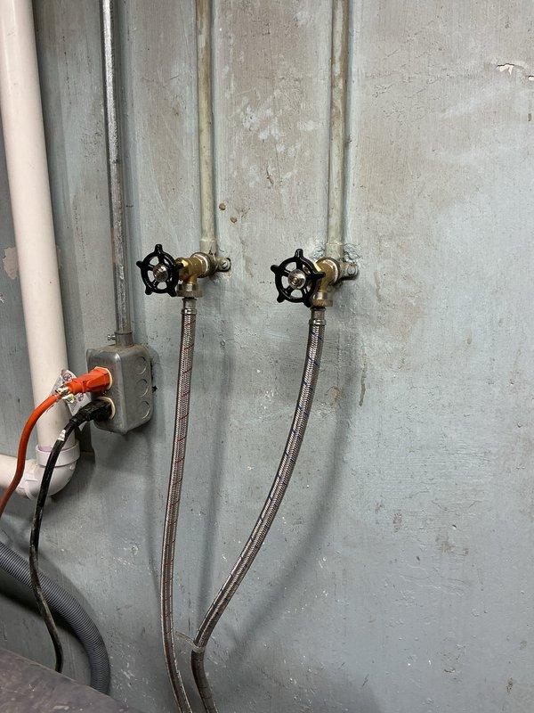 Successfully completed installation of new washer hook-ups, replacing the existing fixtures with two brass water valves featuring black star-shaped handles. Installed new braided stainless steel supply lines and verified proper operation with no leaks.