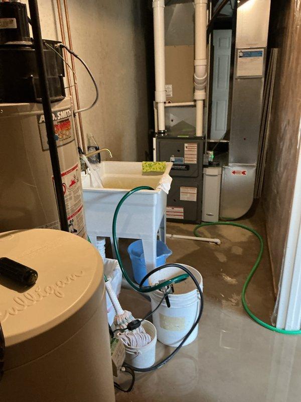 Responded to service call for a 30-year-old A.O. Smith water heater leaking in basement utility room. Performed inspection and determined tank had failed due to age-related corrosion. Shut off water supply using yellow valve handle, drained tank, and advised customer that replacement is necessary as repairs are not viable for unit of this age.