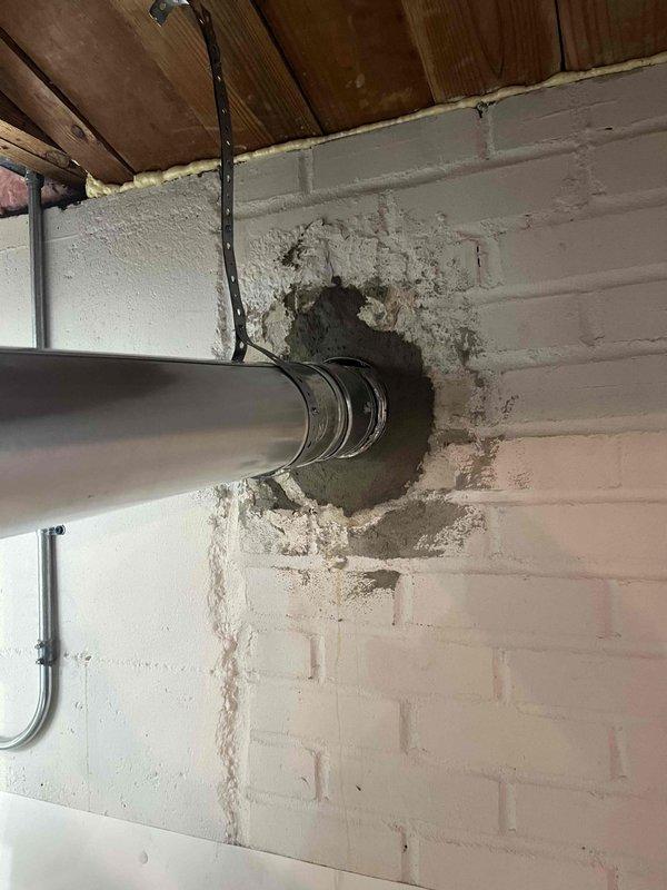 Completed correction on ventilation system per inspector's requirements. Modified single wall vent connection at mortar sleeve, ensuring proper crimping and installation of vent pipe directly to Z-flex liner per manufacturer specifications. Documented completed work with photos showing proper venting through concrete block wall.