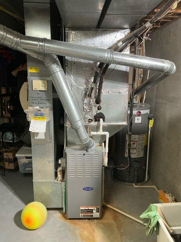 Conducted comprehensive assessment for new air conditioning system installation at side-by-side condo property. Inspected existing outdoor unit location (currently enclosed in protective cage adjacent to brick exterior wall) and evaluated interior Carrier furnace system with connected ductwork in utility room. Documented current system configuration with photographs to facilitate accurate equipment sizing and installation planning for replacement AC system.