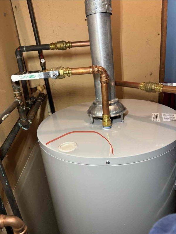 Responded to water leak report for new Bradford White water heater (model WT 10-2026). Inspection revealed leakage at the top near a plastic cap, originating from improperly soldered copper pipe connections. Repaired the faulty T-junction joint and verified proper operation with no further leakage.