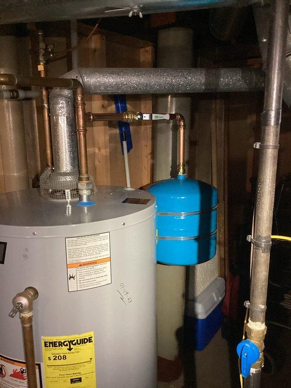 Successfully installed expansion tank on hot water system. Mounted new blue expansion tank vertically with proper copper pipe connections to existing water heater. Verified system operation and checked for leaks after installation.