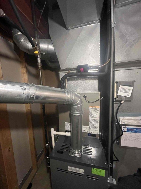 Successfully completed installation of a new Carrier AC system, including indoor furnace unit with properly secured metal ductwork connections and outdoor condenser unit mounted on concrete pad. All refrigerant lines were properly insulated and connected through the home's exterior siding, with system tested and confirmed operational.