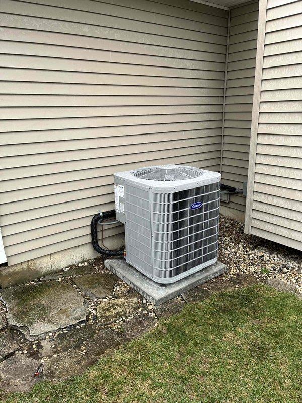 Successfully completed installation of a new Carrier AC system, including indoor furnace unit with properly secured metal ductwork connections and outdoor condenser unit mounted on concrete pad. All refrigerant lines were properly insulated and connected through the home's exterior siding, with system tested and confirmed operational.