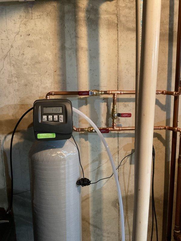 Installed and configured a water softener system in customer's basement. Setup included connecting the main unit with digital control head to existing copper plumbing with appropriate valves, and ensuring proper drainage via clear tubing. System was tested and operational, with the control head programmed and displaying correct time.