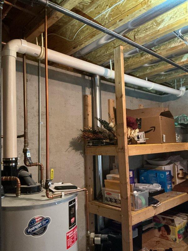 Conducted water heater estimate for customer (CWOW) in basement utility area. Photographed existing installation showing copper and PVC piping connections, valves, and current unit placement adjacent to storage shelving. Documentation completed for potential replacement of residential hot water system under CM 2025.