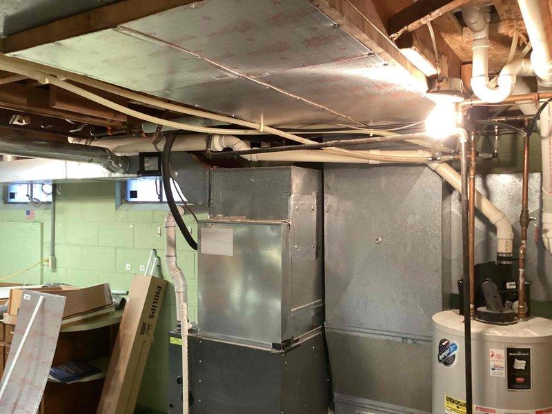 Assessed customer's existing gas water heater for potential replacement. Inspected installation location in basement utility area, noting current unit's connection to gas line and venting system through ceiling. Documented surrounding infrastructure including HVAC system and available space for new unit installation.