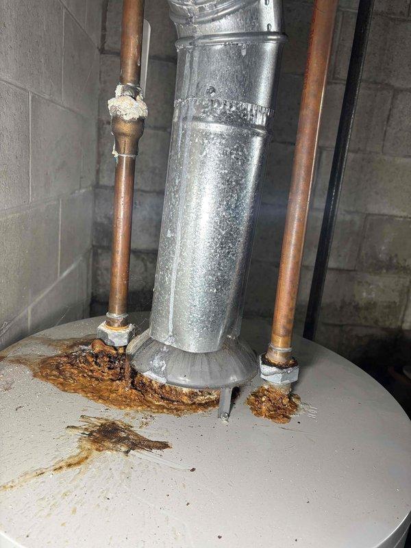 Conducted comprehensive inspection of existing 40-gallon natural draft water heater showing severe corrosion at copper pipe connections and significant rust formation on top surface. Documented extensive oxidation at pipe joints with photographic evidence, indicating potential leaks and end-of-life condition requiring replacement.