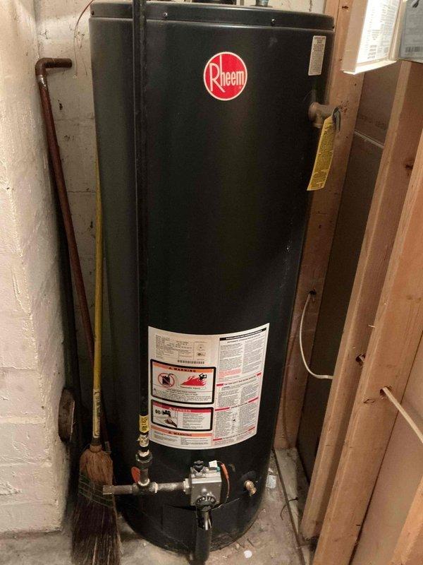 Conducted on-site assessment for toilet installation estimate in a 50-year-old single-family home. Inspected existing Rheem water heater installation in basement utility area, noting proper copper pipe connections, functional vent pipe, and pressure gauge. Documentation photos taken of water heater system to provide comprehensive estimate for requested plumbing project.