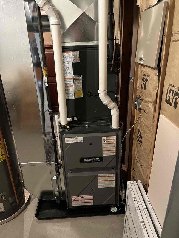 Successfully installed new furnace and air conditioning system in residential mechanical room. Complete installation included proper venting with PVC pipes, placement of the furnace on a drain pan for condensate management, and connection to existing ductwork. System was tested and verified to be in proper working condition with all safety labels affixed and replacement air filters provided.