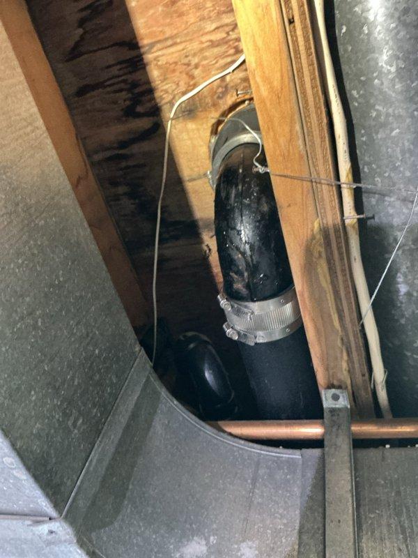 Responded to recurring bathroom plumbing leak in 50-year-old residence. Inspected confined utility access area containing insulated piping with metal connectors and identified corrosion around copper toilet flange as source of water intrusion. Replaced damaged flange and supply line, ensuring proper sealing to prevent future leaks.