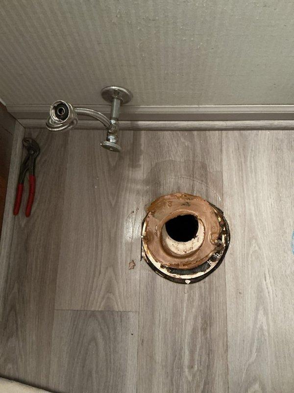 Responded to recurring bathroom plumbing leak in 50-year-old residence. Inspected confined utility access area containing insulated piping with metal connectors and identified corrosion around copper toilet flange as source of water intrusion. Replaced damaged flange and supply line, ensuring proper sealing to prevent future leaks.