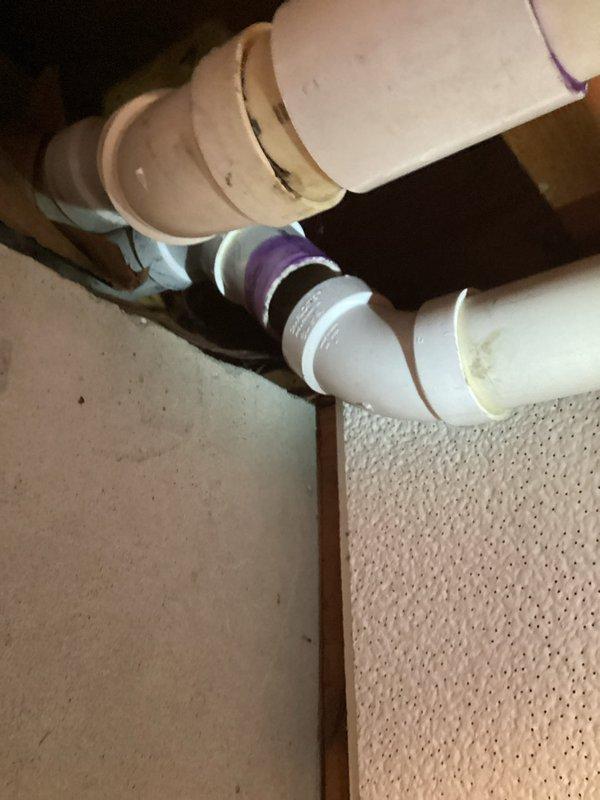 Responded to service call for loose PVC exhaust pipe at a joint on a 3-year-old ENE Wt 08-2028 system. Inspected the PVC ventilation assembly where pipes connect at 90-degree turns, identified a compromised joint with purple primer markings, and properly resealed the connection to restore system integrity and proper venting function.