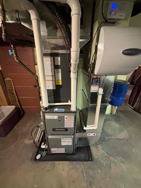 Successfully installed new furnace and air conditioning system with complete ductwork connection and humidifier mounting. System includes proper ventilation with PVC piping, digital control interface, and filter components, all installed according to manufacturer specifications and safety requirements. Unit was placed on appropriate platform in utility room with all necessary connections for optimal performance.