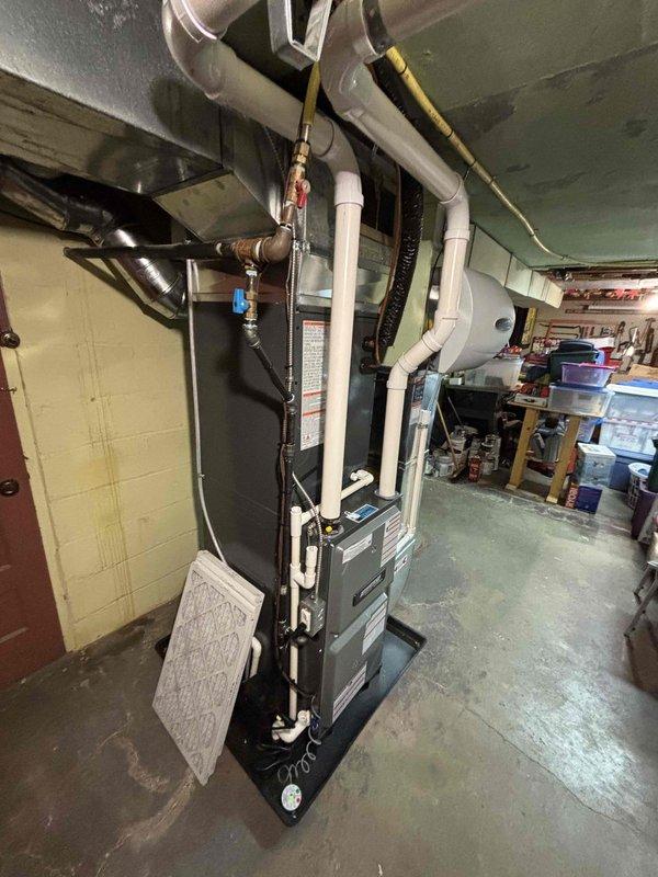 Successfully installed new furnace and air conditioning system with complete ductwork connection and humidifier mounting. System includes proper ventilation with PVC piping, digital control interface, and filter components, all installed according to manufacturer specifications and safety requirements. Unit was placed on appropriate platform in utility room with all necessary connections for optimal performance.