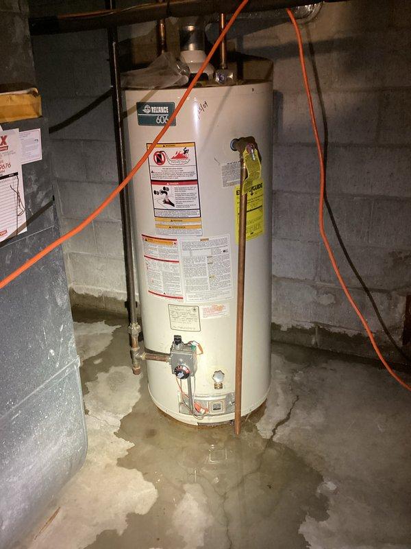 Inspected basement flooding in storage room area where water had been accumulating for four days. Identified water intrusion around pipe penetration through concrete block wall and moisture accumulation around water heater base. Determined that installation of a sump pump system would be the appropriate solution for ongoing water management in this 30+ year old home.