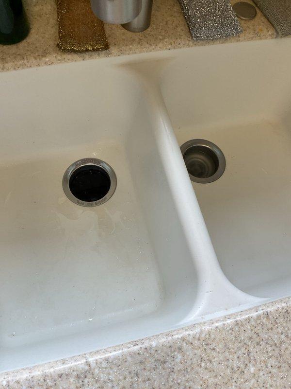 Responded to service call for kitchen sink drain clog persisting for approximately two days in a 1963 residence. Inspected the double-basin kitchen sink and associated PVC P-trap assembly. Successfully cleared blockage in drainage system, restoring proper functionality to the kitchen sink.