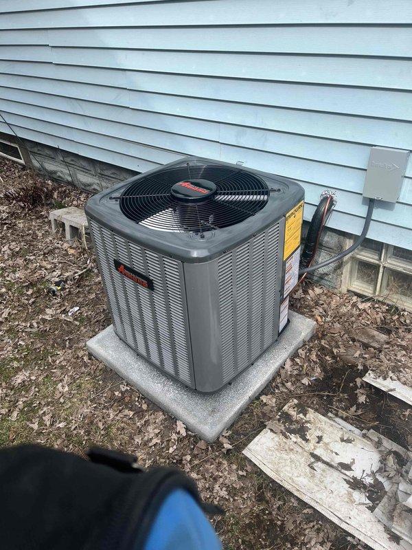 Successfully completed installation of new Amana outdoor air conditioning unit, properly positioned on concrete pad with copper refrigerant lines connected to the home. System includes Rheem furnace and air handler with appropriate galvanized metal ductwork installed in utility area, all components verified operational with proper connections.