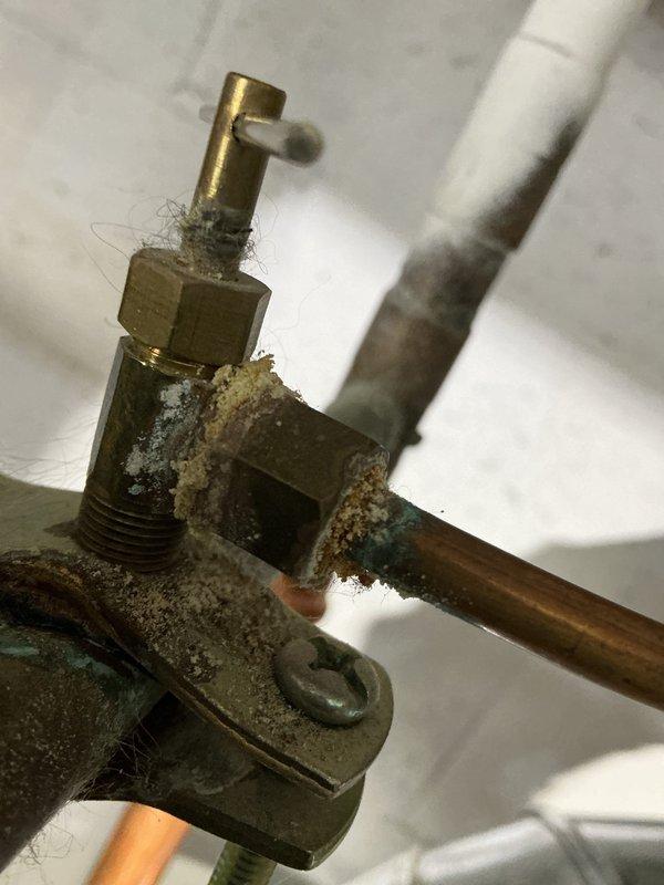 Performed annual heating tune-up on 12-year-old Lennox furnace. Documented significant corrosion and mineral buildup on valve assembly with copper piping connections. Photos taken of corroded brass valve components and mounting infrastructure for service record.